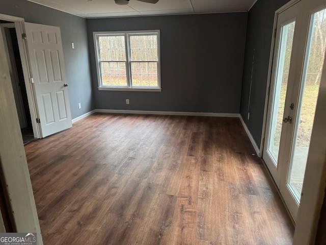 empty room with a wealth of natural light, dark hardwood / wood-style flooring, and ceiling fan