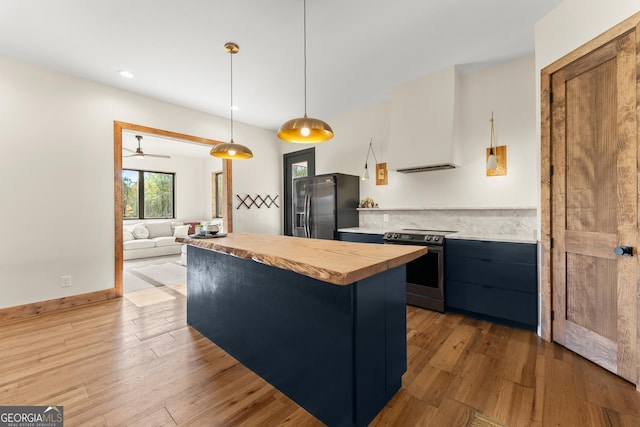 kitchen with decorative light fixtures, wood-type flooring, stainless steel appliances, ventilation hood, and ceiling fan