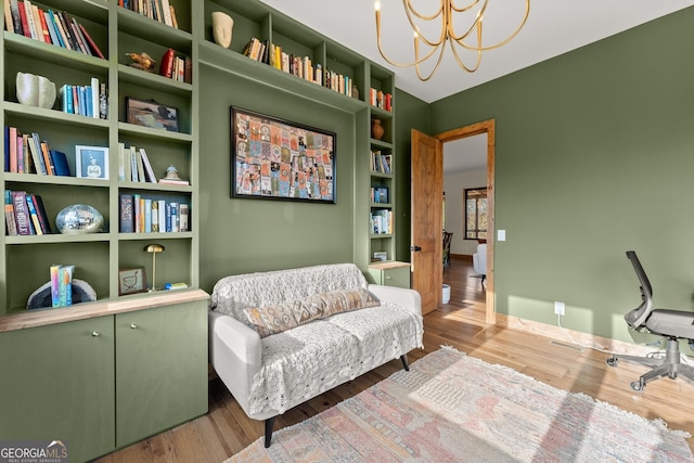 living area with built in shelves, light hardwood / wood-style flooring, and a notable chandelier