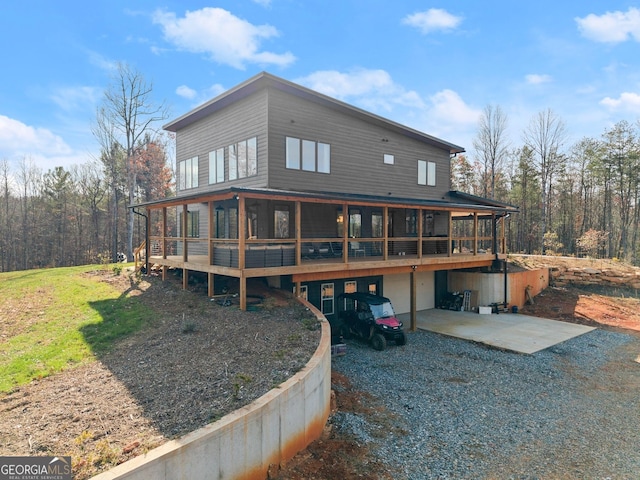 rear view of property featuring a garage, a wooden deck, and a patio