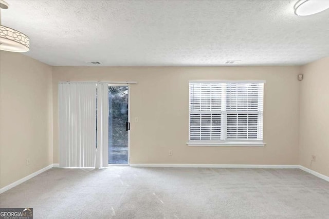 empty room with a textured ceiling and light colored carpet