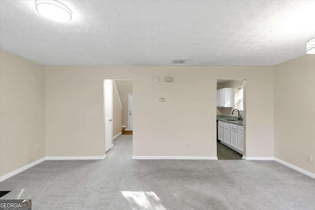 carpeted spare room with a textured ceiling and sink