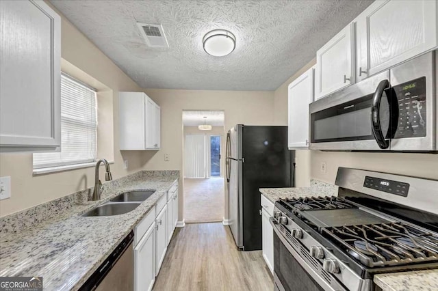 kitchen featuring light hardwood / wood-style flooring, white cabinets, stainless steel appliances, and a textured ceiling