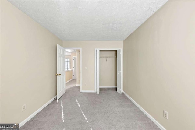 unfurnished bedroom with a textured ceiling, light carpet, and a closet