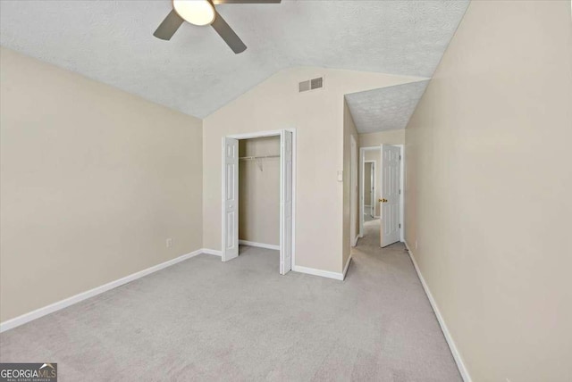 unfurnished bedroom with ceiling fan, a textured ceiling, lofted ceiling, light carpet, and a closet