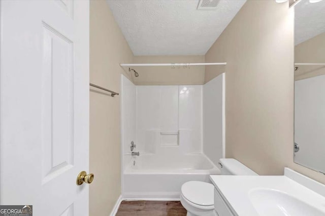 full bathroom featuring tub / shower combination, a textured ceiling, toilet, vanity, and hardwood / wood-style flooring