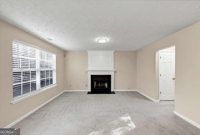 unfurnished living room with a textured ceiling, a large fireplace, and light colored carpet