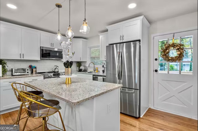 kitchen with white cabinets, a wealth of natural light, a center island, and appliances with stainless steel finishes