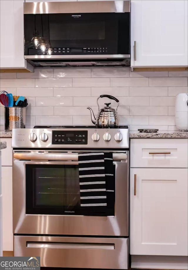 kitchen featuring decorative backsplash, light stone countertops, white cabinetry, and appliances with stainless steel finishes