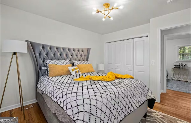 bedroom with a closet, hardwood / wood-style floors, and an inviting chandelier