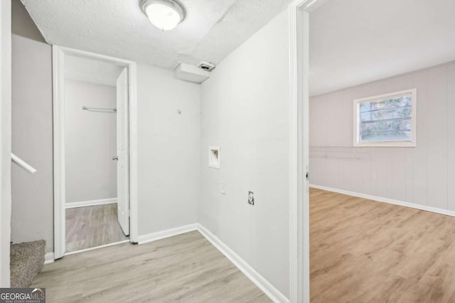 laundry room featuring light wood-type flooring, a textured ceiling, and hookup for a washing machine