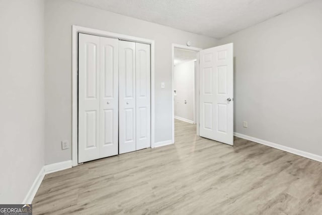 unfurnished bedroom featuring a textured ceiling, light wood-type flooring, and a closet