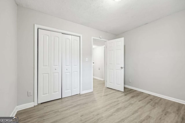 unfurnished bedroom with a closet, a textured ceiling, and light hardwood / wood-style flooring