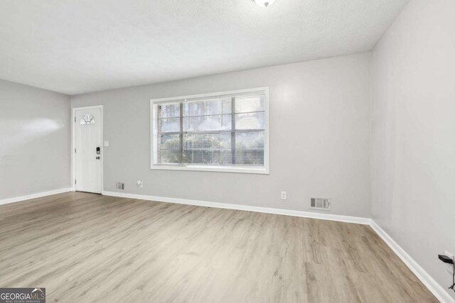 spare room with a textured ceiling and light wood-type flooring