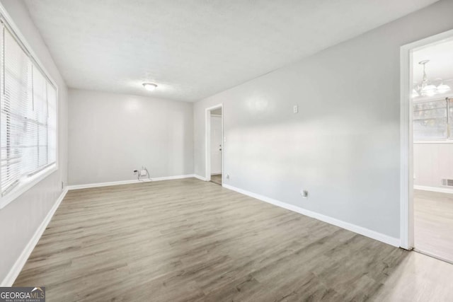 spare room featuring hardwood / wood-style floors and a notable chandelier