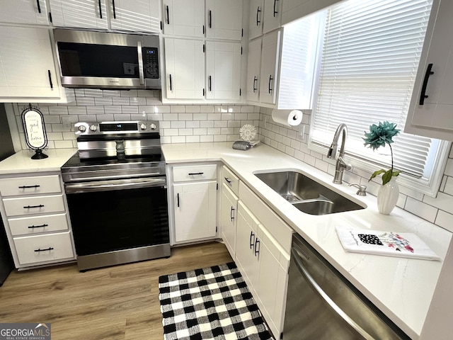 kitchen featuring white cabinets, appliances with stainless steel finishes, decorative backsplash, and sink