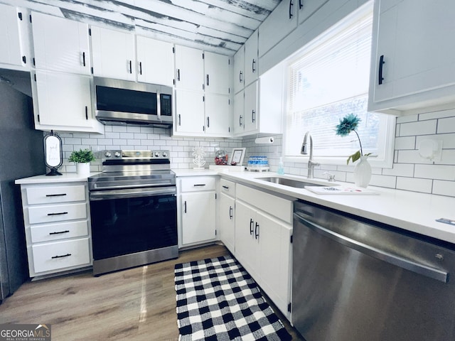 kitchen with light wood finished floors, tasteful backsplash, appliances with stainless steel finishes, and light countertops