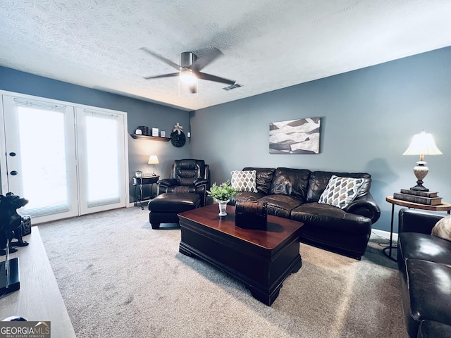 living room with a ceiling fan, carpet, visible vents, and a textured ceiling