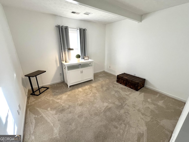 interior space featuring carpet, visible vents, beamed ceiling, and a textured ceiling