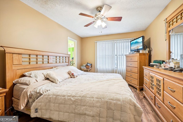 bedroom featuring ceiling fan, dark hardwood / wood-style flooring, and a textured ceiling