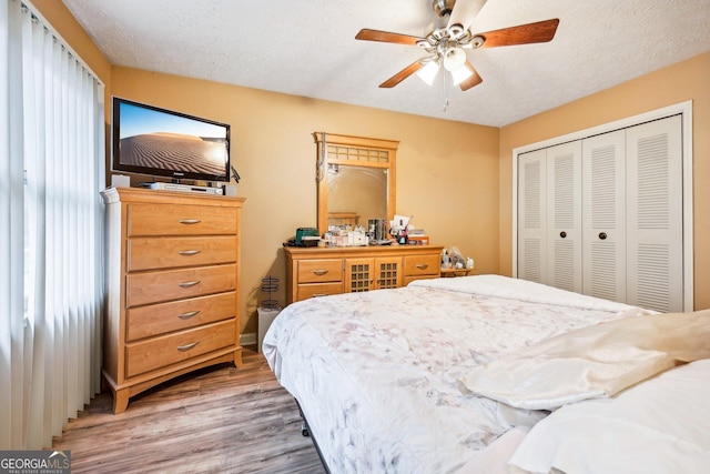 bedroom with wood-type flooring, a textured ceiling, a closet, and ceiling fan