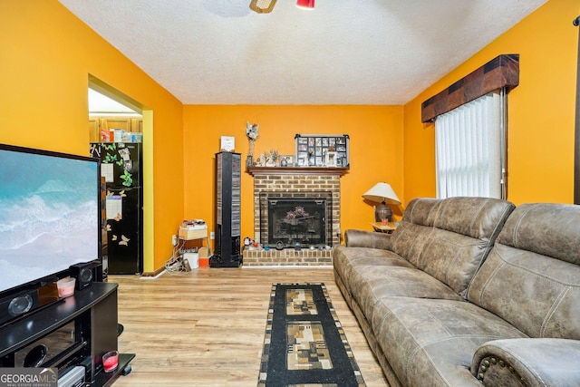 living room featuring a fireplace, wood-type flooring, and a textured ceiling