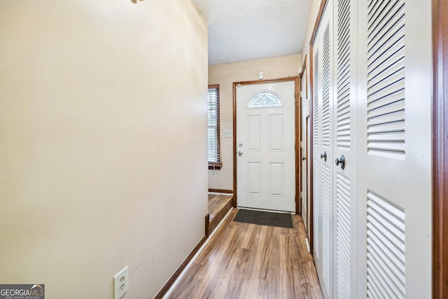 entryway with light hardwood / wood-style floors and a textured ceiling