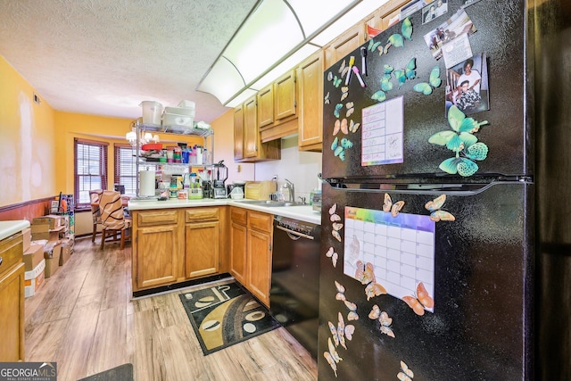 kitchen with black appliances, sink, light hardwood / wood-style flooring, a textured ceiling, and kitchen peninsula