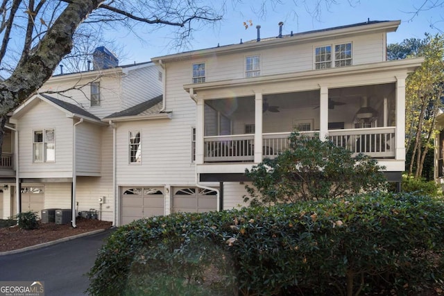 back of property with central AC, a garage, and a sunroom