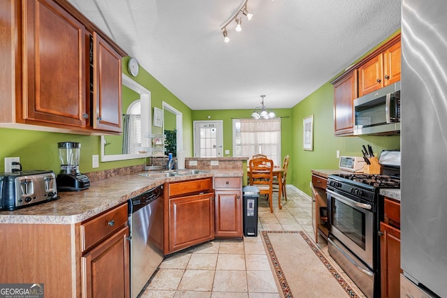 kitchen featuring hanging light fixtures, sink, light tile patterned floors, appliances with stainless steel finishes, and a notable chandelier