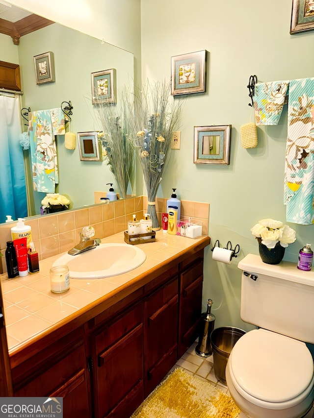 bathroom featuring decorative backsplash, tile patterned floors, ornamental molding, vanity, and toilet