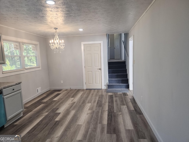 interior space with a textured ceiling, dark hardwood / wood-style floors, an inviting chandelier, and ornamental molding