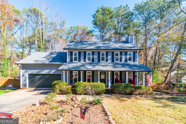 colonial inspired home with a front yard, a porch, and a garage