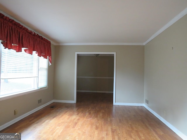 empty room featuring hardwood / wood-style floors and crown molding