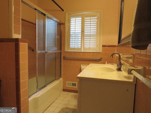 bathroom with tile patterned floors, vanity, shower / bath combination with glass door, and tile walls