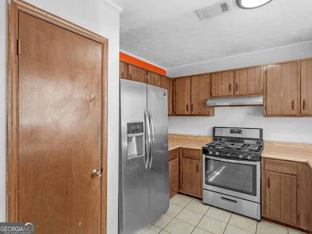 kitchen featuring light tile patterned floors, a textured ceiling, stainless steel appliances, and crown molding