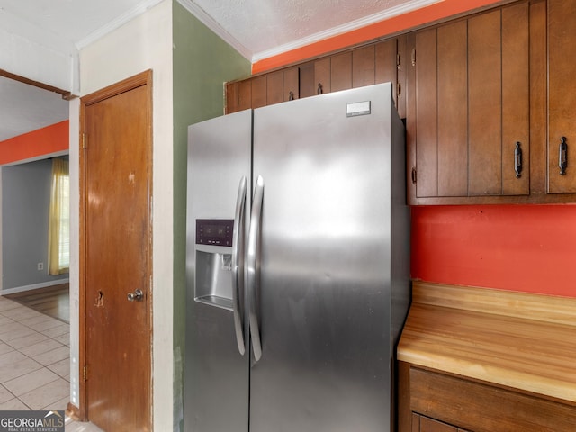 kitchen with stainless steel fridge, crown molding, and light tile patterned flooring