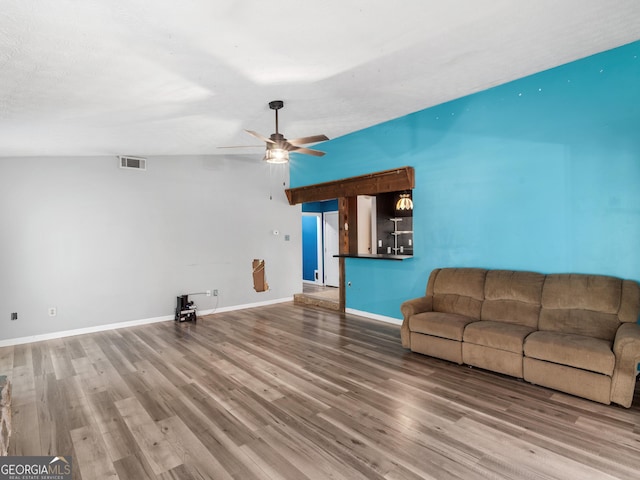 unfurnished living room featuring hardwood / wood-style flooring, ceiling fan, lofted ceiling, and a textured ceiling