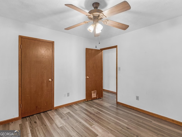 empty room featuring a textured ceiling, light wood-type flooring, and ceiling fan