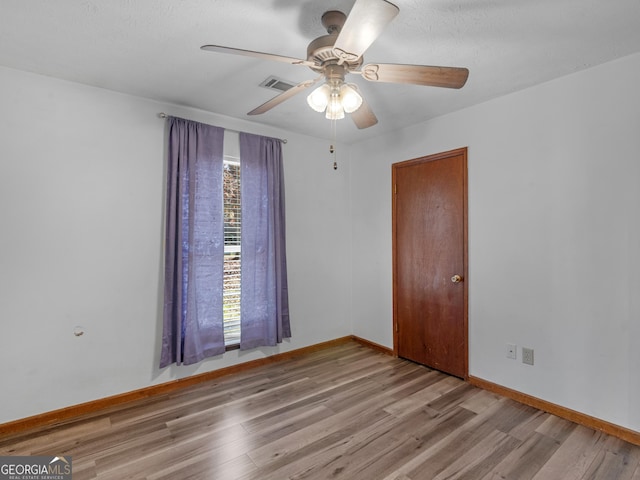 empty room featuring a textured ceiling, light wood-type flooring, and ceiling fan