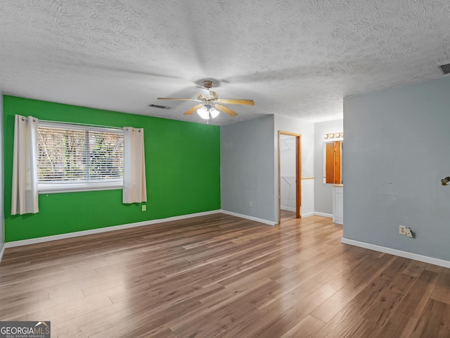 unfurnished room with hardwood / wood-style flooring, ceiling fan, and a textured ceiling