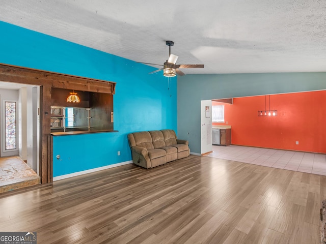 unfurnished living room featuring ceiling fan, wood-type flooring, a textured ceiling, and vaulted ceiling