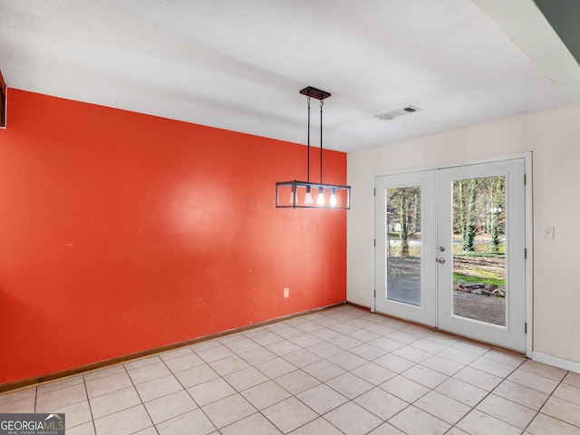 unfurnished dining area with french doors, a textured ceiling, and light tile patterned floors