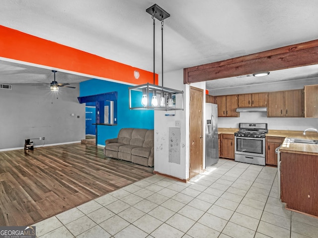 kitchen featuring pendant lighting, ceiling fan, light wood-type flooring, a textured ceiling, and appliances with stainless steel finishes