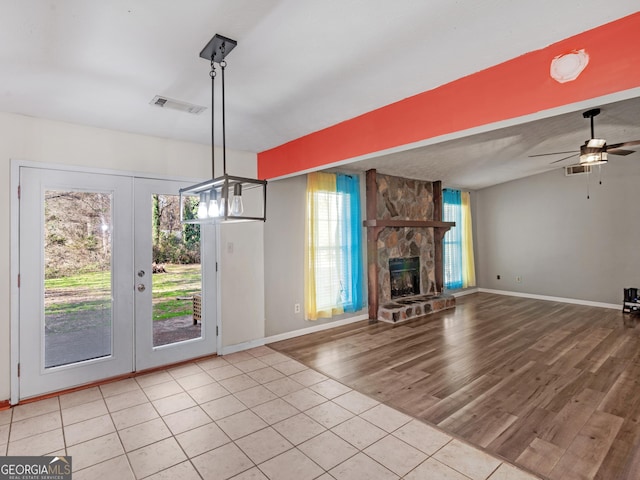 unfurnished living room featuring light hardwood / wood-style flooring, plenty of natural light, a stone fireplace, and ceiling fan