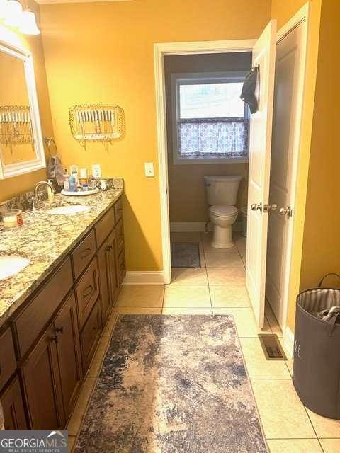 bathroom with toilet, vanity, and tile patterned floors