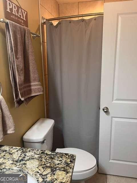 bathroom featuring tile patterned floors, toilet, and walk in shower