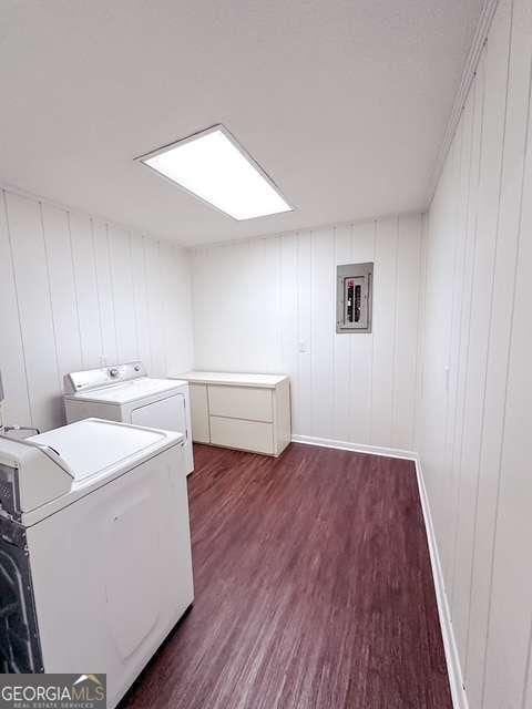 clothes washing area featuring washer and clothes dryer, dark wood-type flooring, wooden walls, and a skylight