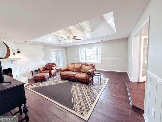 living room featuring a raised ceiling, french doors, dark hardwood / wood-style floors, and a brick fireplace