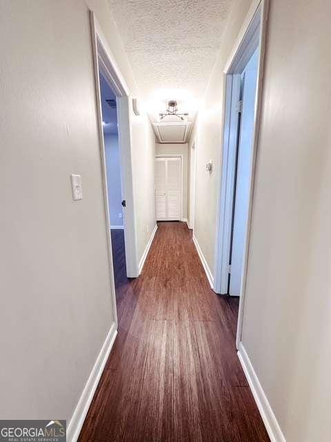 corridor featuring dark hardwood / wood-style floors and a textured ceiling